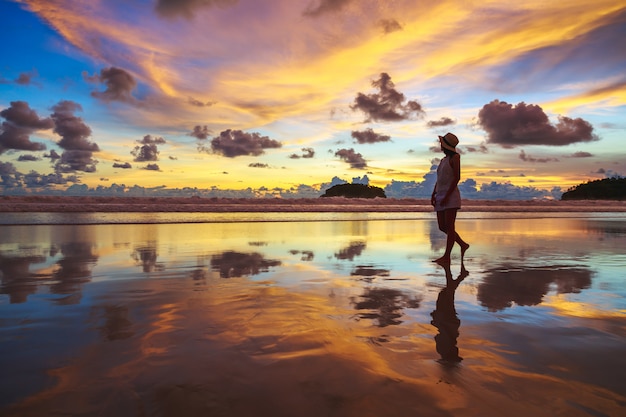 Sommerreiseferienkonzept, Reisende asiatische Frau mit Hut entspannen und Sightseeing am Kata-Strand bei Sonnenuntergang in Phuket, Thailand