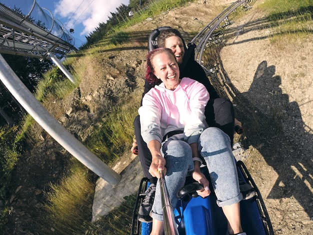 Sommerrodelbahn Rodelbahn mit vielen Kurven auf einem Berg. Alpine Coaster im Sommer und Herbst schöne Landschaften. Schneller Fahrspaß von jungen Paarreisen.