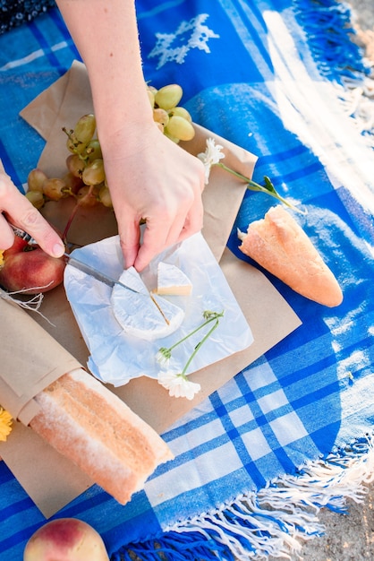 Sommerromantisches Picknick mit Obst, Käse, Wein, Brot, Trauben, Pfirsich. Licht von den ersten Sonnenstrahlen.