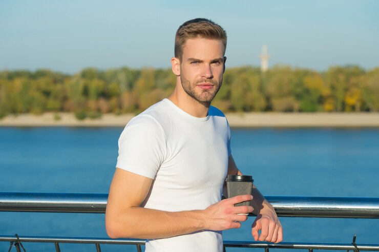 Foto sommerruhe. ort der macht. mannhippie, die am naturhintergrund des flusses sich entspannt. schöner kerl im freien sonniger tag. reiseziele für den sommerurlaub. allein mit seinen gedanken entspannen. sommermorgen.