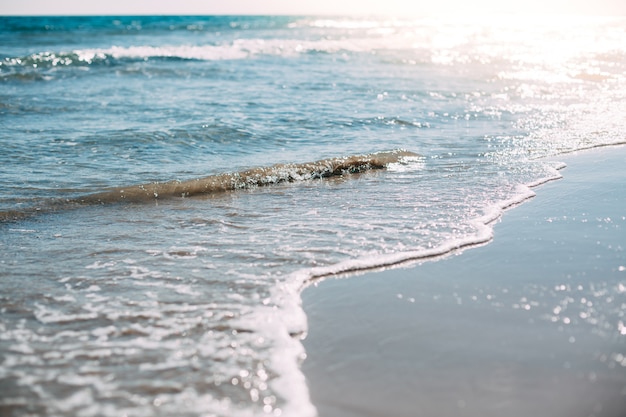 Sommersandstrand und Küstenwellen