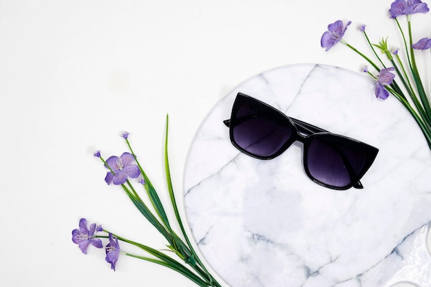Sommersonnenbrille auf Marmorbrett oder Podium mit Genariumblumen