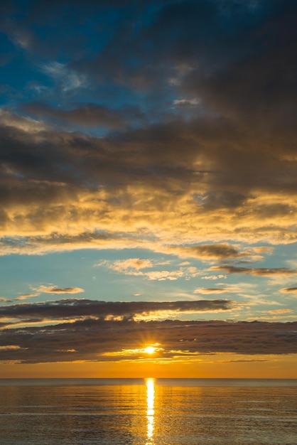 Sommersonnenuntergang am Strand mit Wolken über dem Himmel