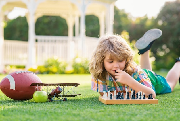 Sommerspiele und Outdoor-Aktivitäten für Kinder Kind spielt Schachspiel im Frühlings-Hinterhof, der auf g liegt