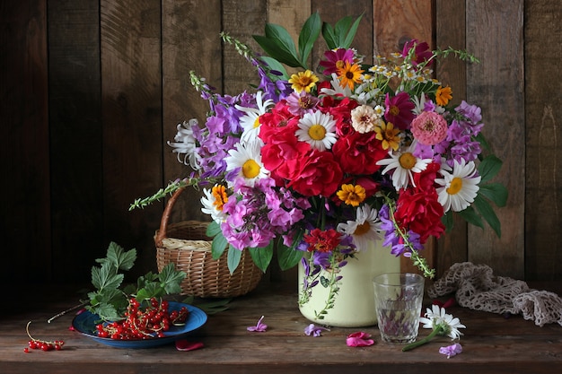 Sommerstillleben mit einem Strauß Gartenblumen und roter Johannisbeere.