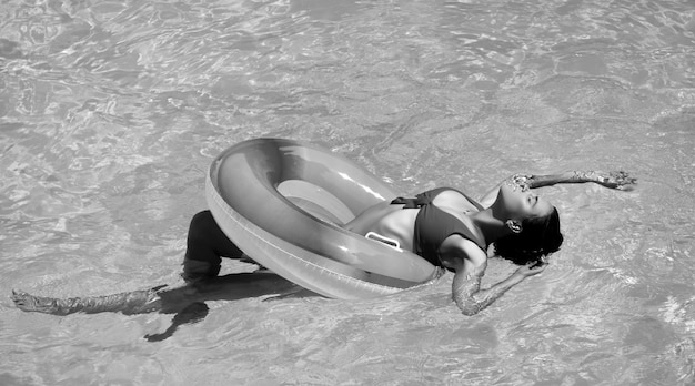 Sommerurlaub genießen sonnenbräune frau im badeanzug auf aufblasbarem kreis im schwimmbad