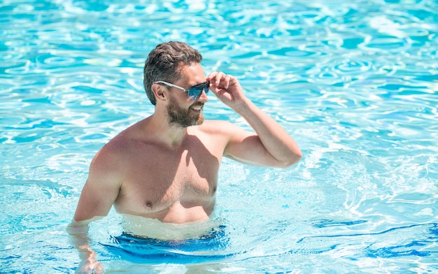 Sommerurlaub Guy trägt eine Brille im Wasser Freizeit und freier Tag entspannen beim Schwimmen entspannen Sommer-Spa-Resort-Urlaub Glücklicher sexy Mann im Schwimmbad Pool-Party Sommerstimmungskonzept