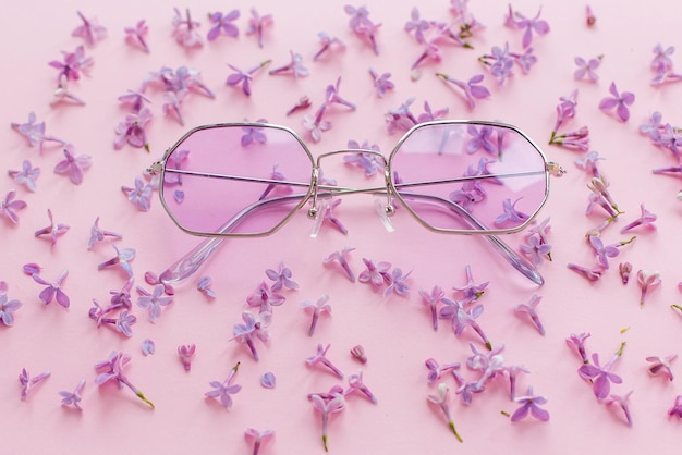 Foto sommerurlaub und festivalkonzept stilvolle lila boho-sonnenbrille auf rosa hintergrund mit lila blumen kreative trendige wohnung lag mit platz für text, moderne mode und mädchenhaftes bild