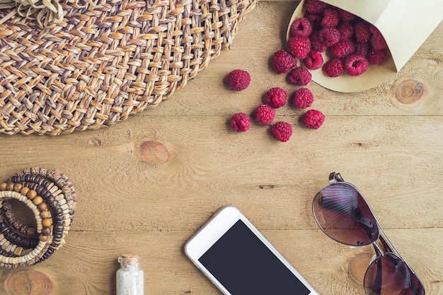 Sommerurlaub Urlaub Entspannungskonzept Himbeeren Strohhut Smartphone Sonnenbrille von oben