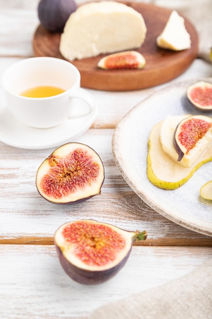 Sommervorspeise mit Birne, Hüttenkäse, Feigen und Honig auf weißem Holzhintergrund und Leinengewebe. Seitenansicht, Nahaufnahme, selektiver Fokus.