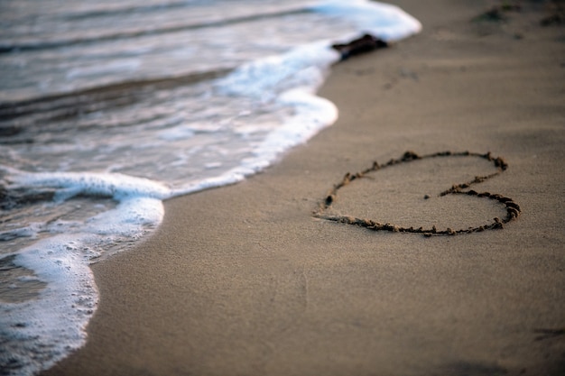 Sommerzeit, Herz auf Sand vom Meer gemalt