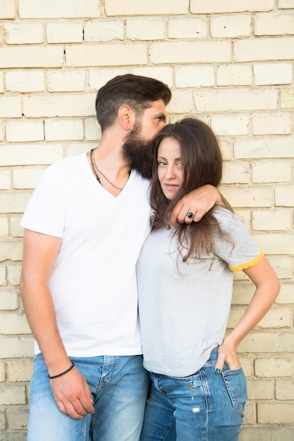 Somos apenas um casal apaixonado. casal apaixonado, abraçando-se na parede de tijolos. casal da família de homem barbudo e mulher sexy. casal sensual em estilo casual.