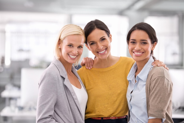 Somos el equipo que necesitas. Retrato recortado de tres empresarias de pie en la oficina.