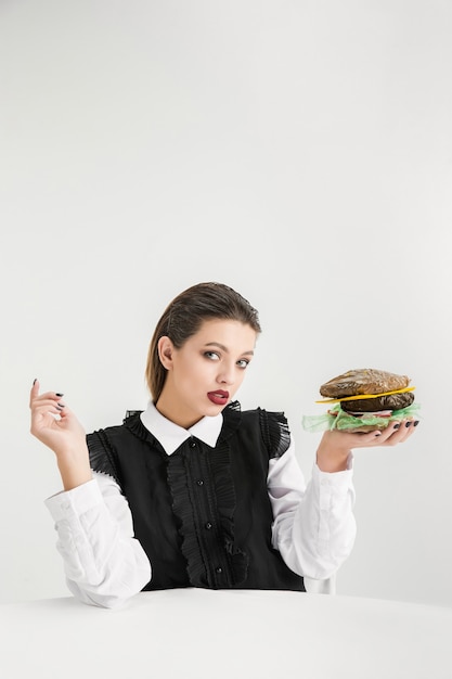 Somos lo que comemos. Mujer comiendo hamburguesa de plástico, concepto ecológico. Hay tantos polímeros que simplemente estamos hechos de ellos. Desastre ambiental, moda, belleza, comida. Perdiendo mundo orgánico.