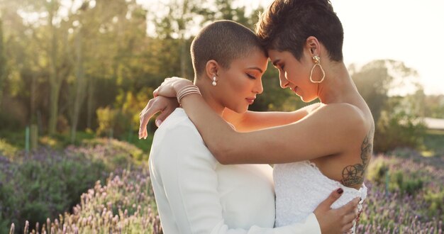 Estos son dos seres humanos que fueron hechos el uno para el otro Captura recortada de una cariñosa pareja de lesbianas jóvenes de pie con los brazos alrededor de la otra en un prado el día de su boda