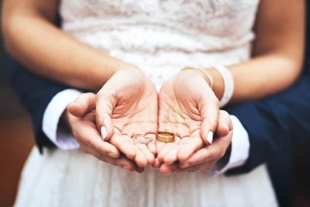 Estos son símbolos de nuestro amor y compromiso Captura recortada de una pareja de recién casados irreconocibles sosteniendo y mostrando sus anillos el día de su boda