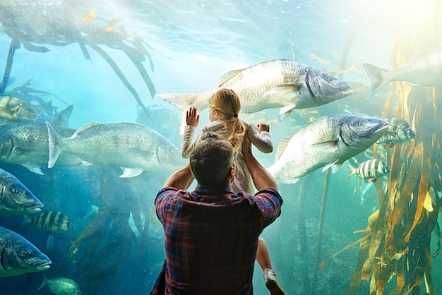 Son tan grandes como yo Papá Captura recortada de un padre y su pequeña hija mirando una exhibición en un acuario