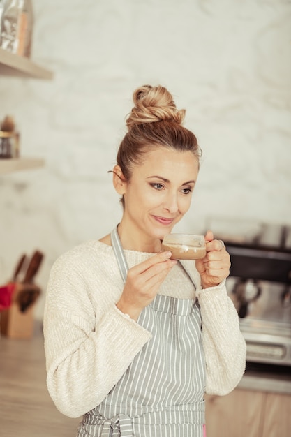 Soñador. Hermosa mujer pensativa sonriendo y sosteniendo su taza de café.