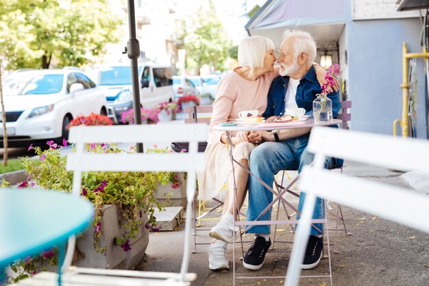 Soñadora pareja senior sentada en el café y abrazar