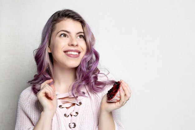 Soñando joven modelo con cabello morado con sabroso postre con bayas. Espacio para texto