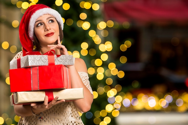 Soñando pensando feliz mujer hermosa pensativa con sombrero rojo santa claus / regalos, navidad, concepto de Navidad