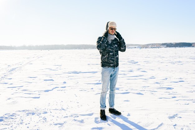 Soñar con hombre elegante en gafas de sol posando en el campo de nieve