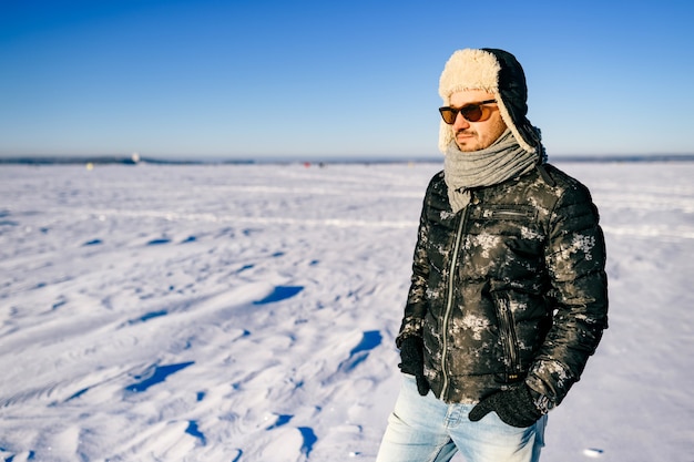 Soñar con hombre elegante en gafas de sol posando en el campo de nieve