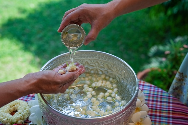 Songkran oder thailändisches Neujahrsfest Thai Traditional Gießen Sie Wasser auf die Hände der verehrten Ältesten