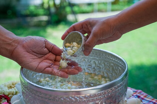 Songkran oder thailändisches Neujahrsfest Thai Traditional Gießen Sie Wasser auf die Hände der verehrten Ältesten