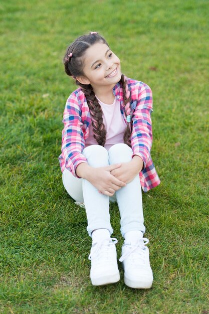 Sonhando o dia Parques e sonhador alegre ao ar livre Primavera natureza Piquenique de verão Menina da escola pequena com cabelo na moda infância feliz menina pequena relaxa na grama verde Sonhando com férias