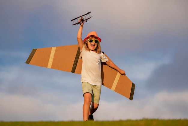 Sonho de voar Crianças pequenas com avião de brinquedo em um campo ao pôr do sol Conceito de sucesso e líder infantil Menino sonha em se tornar um piloto