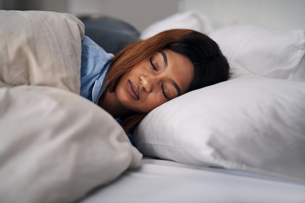 Sonido dormido Captura recortada de una atractiva joven durmiendo tranquilamente en la cama en casa