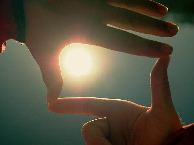 Foto sonne auf weiblicher hand silhouette einer hand, die die sonne hält sonne tief über dem wasserniveau schönes schattenspiel