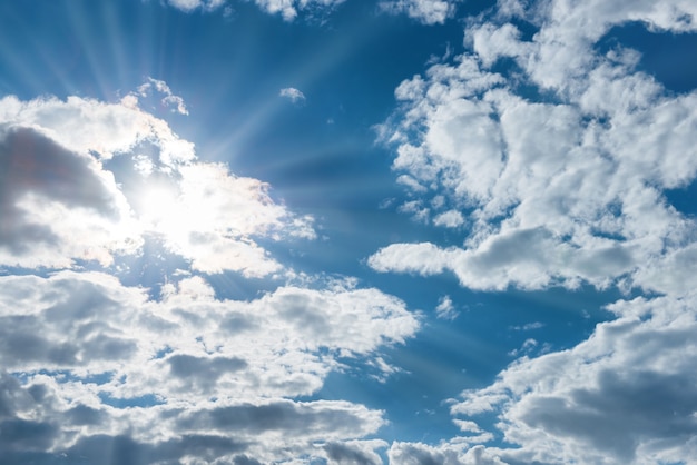 Sonne scheint durch weiße Wolken am blauen Himmel als Naturhintergrund