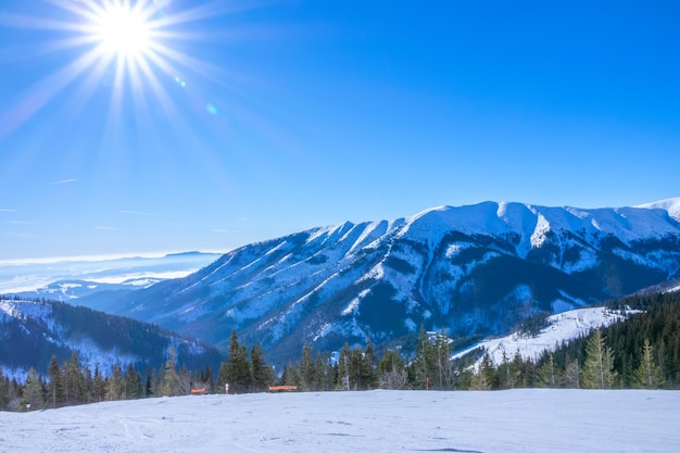 Sonne über leerer Skipiste und Bergrelief