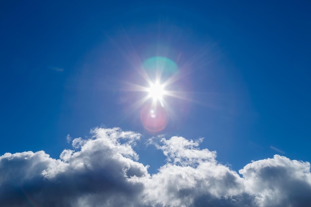 Sonne über weißer Wolke auf blauem Himmelshintergrund mit natürlichen Blendenflecken