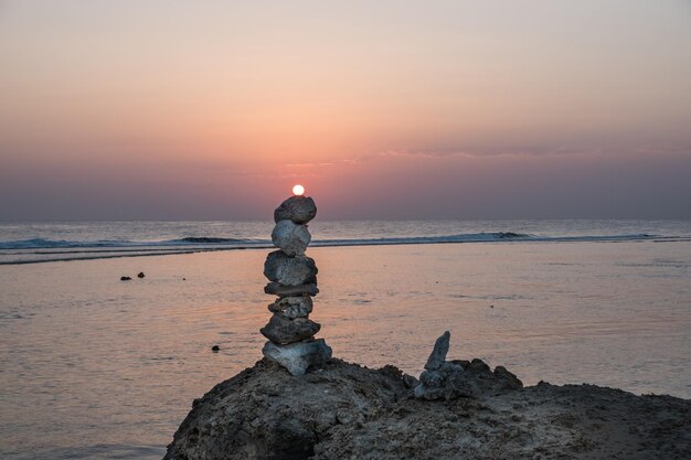 Sonne während des Sonnenaufgangs liegt auf einem gestapelten Turm aus Korallen am Strand