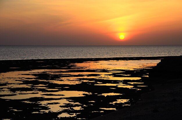 Sonnenaufgang am Meer mit Reflexionen am Strand