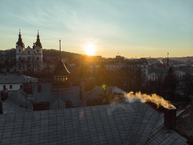 Sonnenaufgang über der Stadt. Rauch aus dem Schornstein des Hauses. Luftaufnahme