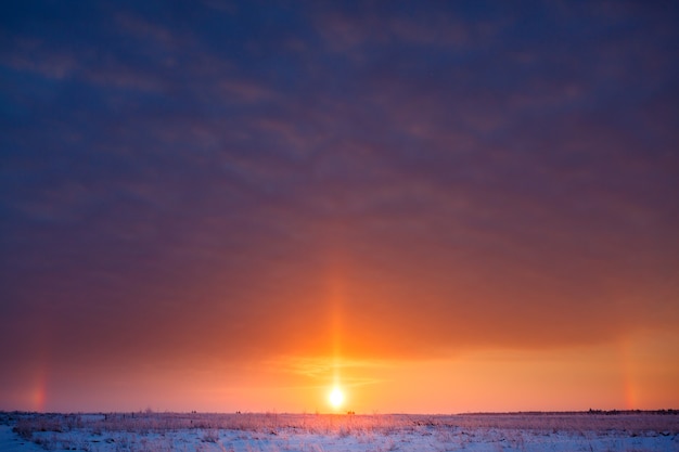 Sonnenaufgang über der Wiese im Winter bei starkem Frost.