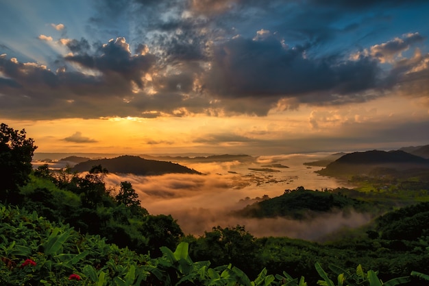 Sonnenaufgang über einem Gebirgstal. Schönes Bild des grünen Tals in der Nähe des Flusses in einer natürlichen landschaftlichen Umgebung des Sommers. Ein schöner Tag am Wasser. Morgennebel schafft eine friedliche Atmosphäre.