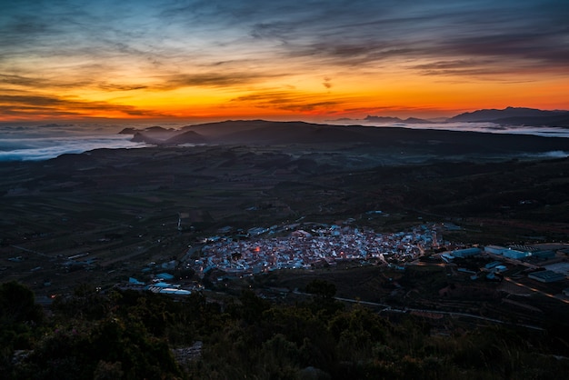 Sonnenaufgang über einem Tal zwischen Bergen mit Nebel La Font De La Figuera Valencia Spain