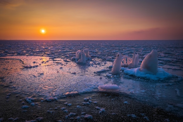 Sonnenaufgang und gefrorenes Meer Schöne Winterlandschaft mit See und roter Sonne in der Morgenzeit Tagesanbruch