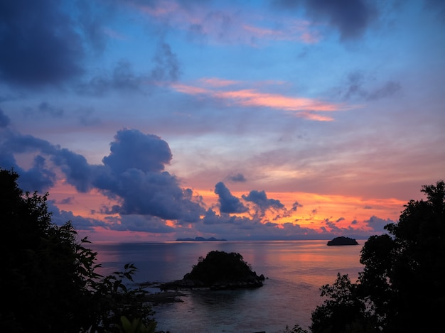 Foto sonnenaufgangseeansicht mit kleiner insel und bunter himmel durch baum verlässt schattenbild