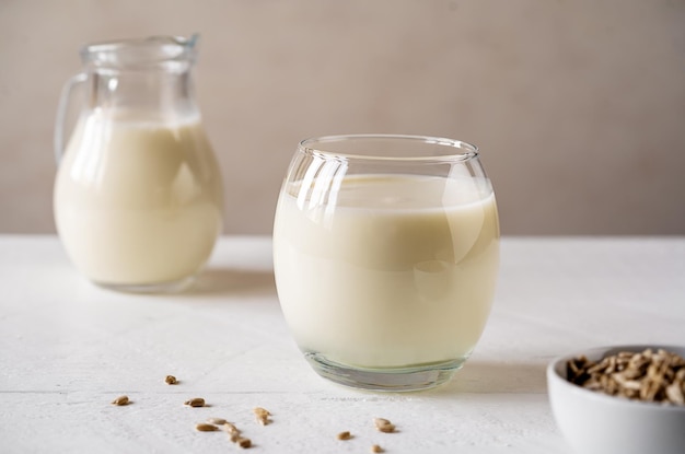 Sonnenblumenmilch im Glas mit Rohmilchglas auf weißem Holzhintergrund