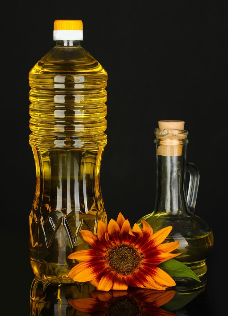 Foto sonnenblumenöl in einer plastikflasche und kleine karaffe auf schwarzem hintergrund isoliert