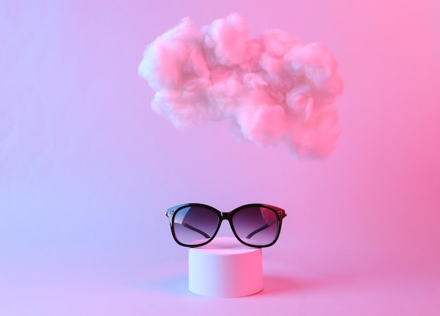 Sonnenbrille mit schwebender, flauschiger Wolke in rosa blauem Neonlicht Schönheits- und Modeschaufenster Konzeptkunst Minimalistische Idee