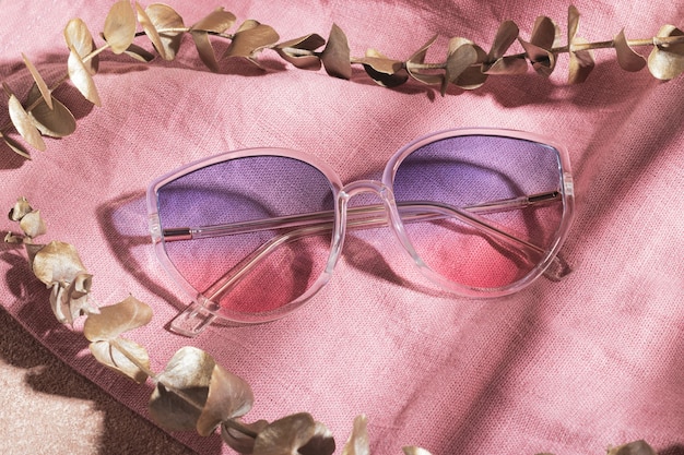 Sonnenbrille mit transparentem Rahmen und Farbverlauf auf rosa Baumwollstoff