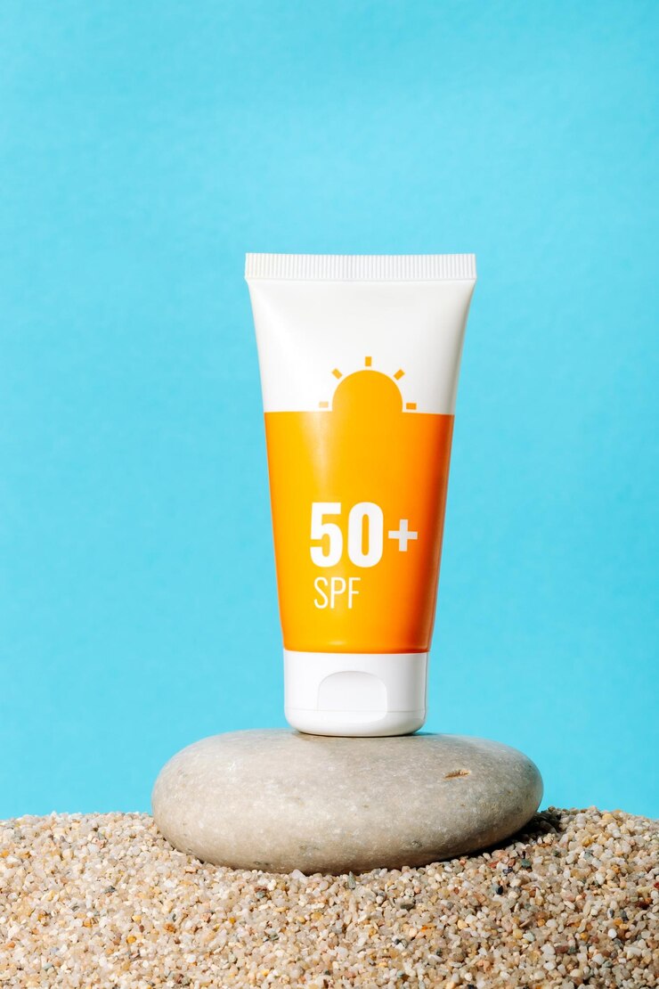 Sonnencreme in einer orangefarbenen Tube auf blauem Hintergrund mit Strandsand-Kopierraum Sommer-Strandurlaubskonzept SPF-UV-Protect-Kosmetik