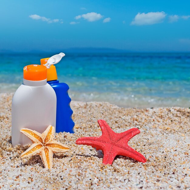 Sonnencremeflaschen und Seesterne am Strand